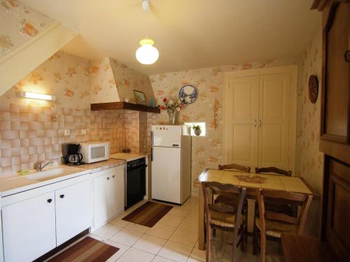 une cuisine avec une table et un réfrigérateur blanc dans l'établissement Cottage near Lac du Causse with Terrace, cleaning included, à Chasteaux
