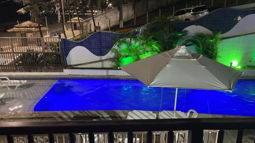 an umbrella sitting next to a swimming pool at night at Flat completo a beira mar com vista exuberante - pé-na-areia mesmo! in Natal