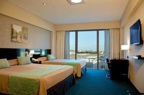 レシステンシアにあるGala Hotel y Convencionesのベッド2台とバルコニーが備わるホテルルームです。