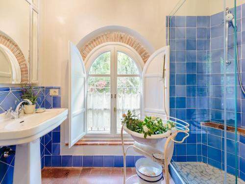a blue tiled bathroom with a toilet and a window at Tuscan Farmhouse with Infinity Pool Retreat in Matraia