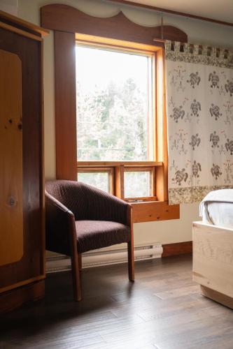a bedroom with a chair in front of a window at Auberge Saint-Mathieu in Saint Mathieu Du Parc