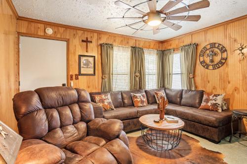 a living room with a leather couch and a ceiling fan at The Lazy Spur in Bandera