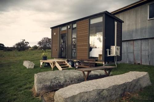 a tiny house with a picnic table in a field at Farm Stay Tiny House by Tiny Away in Braidwood