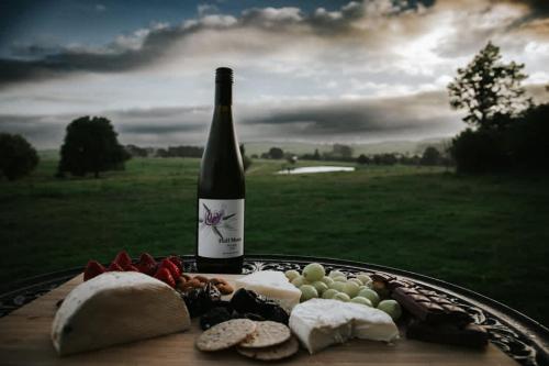 a bottle of wine sitting next to a plate of food at Farm Stay Tiny House by Tiny Away in Braidwood