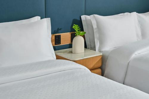 a bedroom with two beds and a vase with a plant on a side table at The St. Regis Cap Cana Resort in Punta Cana