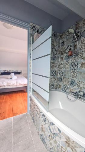 une salle de bain avec baignoire et un lit dans une chambre dans l'établissement Villa des Jardins, maison familiale 14 personnes proche plage, à Villers-sur-Mer