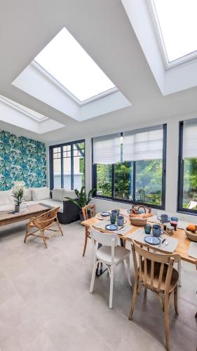 un salon avec une table, des chaises et des fenêtres dans l'établissement Villa des Jardins, maison familiale 14 personnes proche plage, à Villers-sur-Mer