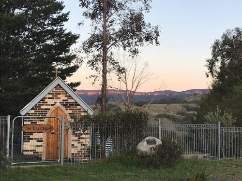 a small chapel with a wooden door and a fence at Tiny Nanook - Kanimbla Valley by Tiny Away in Kanimbla