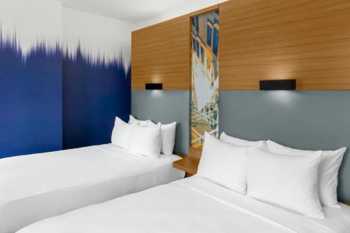 two beds in a hotel room with white pillows at Aloft New York Brooklyn in Brooklyn