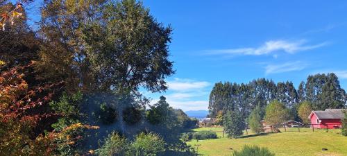 a farm with a red house and a field with trees at Refugio Verde Apartamento entero con entrada independiente in Puerto Varas