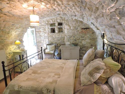 a bedroom with a bed and a stone wall at La Flor Azul in Grospierres