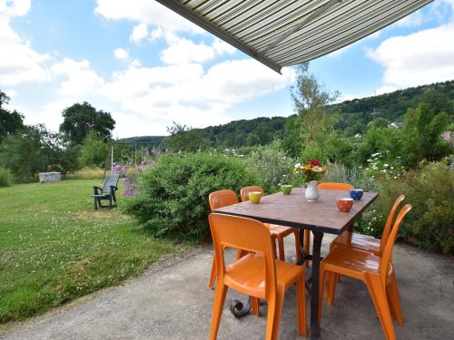a wooden table with orange chairs and a garden at Modern holiday home in Crux-La-Ville with terrace in Crux-la-Ville