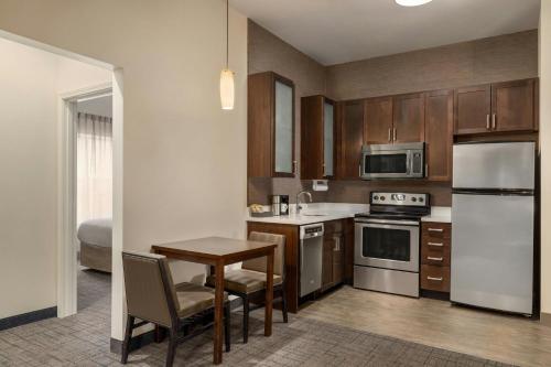 a kitchen with wooden cabinets and a table and a refrigerator at Residence Inn by Marriott Albany Washington Avenue in Albany