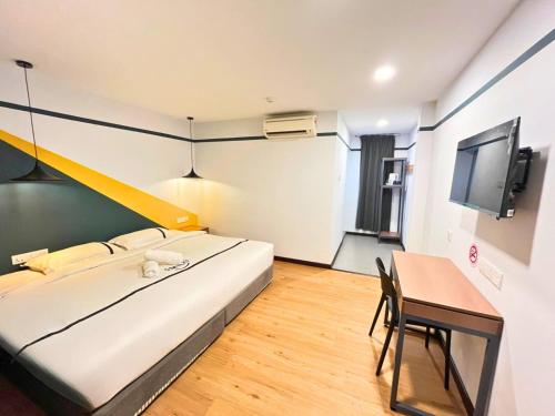 a bedroom with a bed and a table and a tv at Sky Hotel Cheras Maluri in Kuala Lumpur