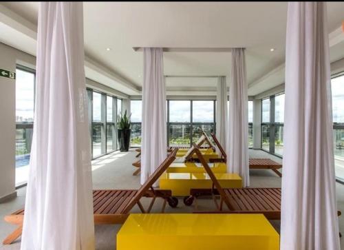 a living room with a yellow table and large windows at Studio com Garagem e Piscina Aquecida Centro in Curitiba