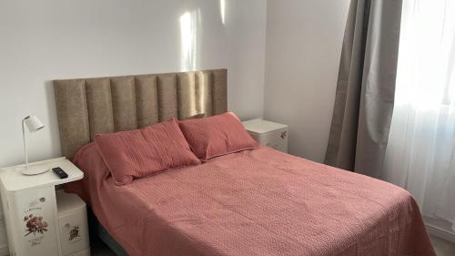 a small bedroom with a bed with a red blanket at Duplex Geronimo in Puerto Madryn