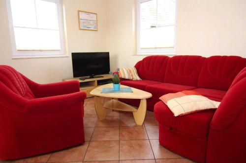 a living room with two red couches and a tv at Semi detached house Kuehlungsborn in Kühlungsborn