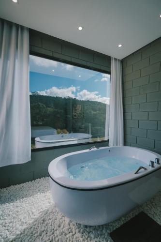 a bath tub in a bathroom with a large window at Blockhaus in Rancho Queimado