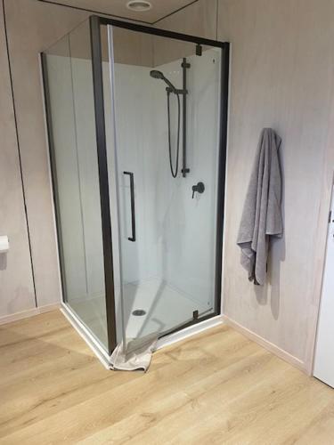 a shower with a glass door in a bathroom at Point Wells Holiday Apartment in Big Omaha