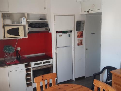 - une petite cuisine avec des appareils blancs et des murs rouges dans l'établissement Bel Appartement T2 Proche Plage à Leucate, Terrasse, Parking, 4 Pers. - FR-1-798-15, à Leucate