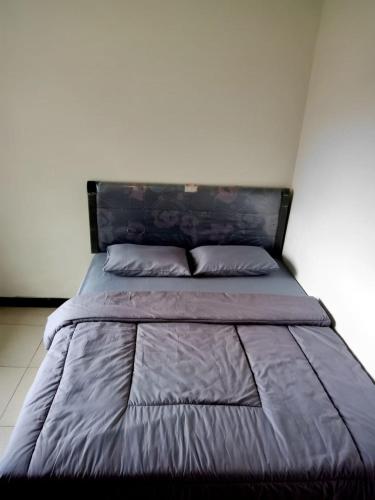 a bed with a blue comforter and two pillows at Ikiikahomestay in Probolinggo