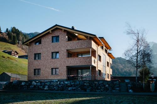 a large brick house on top of a hill at Kanis Appartements in Schoppernau