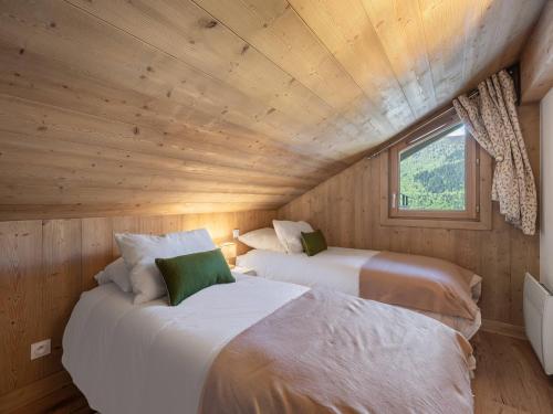 Cette chambre en bois dispose de 2 lits et d'une fenêtre. dans l'établissement Appartement rénové, 3 chambres, proche pistes, terrasse - FR-1-566-78, à Les Allues