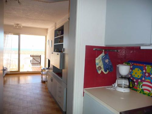 une cuisine avec un comptoir blanc et un mur rouge dans l'établissement Studio Cabine RDC, 4 Pers, Accès Direct Plage - FR-1-782-78, au Barcarès