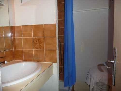 La salle de bains est pourvue d'une baignoire et d'un rideau de douche bleu. dans l'établissement Appartement 2 pièces, accès plage, parking privé, Le Barcarès - FR-1-782-79, au Barcarès