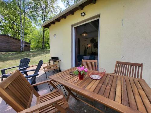 une table et des chaises en bois sur une terrasse dans l'établissement Retraite paisible en maisonnette au bord d'un lac - FR-1-839-3, à La Coquille