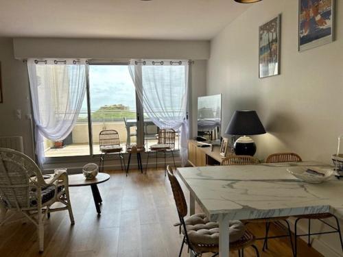- un salon avec une table, des chaises et une grande fenêtre dans l'établissement Bel appartement T3 rénové avec vue sur mer à Royan - FR-1-494-213, à Royan
