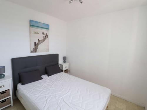 - une chambre avec un lit blanc et une photo sur le mur dans l'établissement 2 pièces avec loggia, piscine à 200m de la plage - FR-1-307-289, au Grau-du-Roi