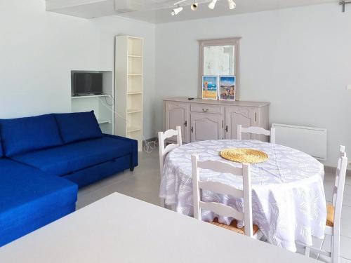 un salon avec une table et un canapé bleu dans l'établissement Studio cosy à Saint-Aubin-sur-Mer, idéal pour 2 personnes, près des plages du débarquement - FR-1-746-32, à Saint-Aubin-sur-Mer