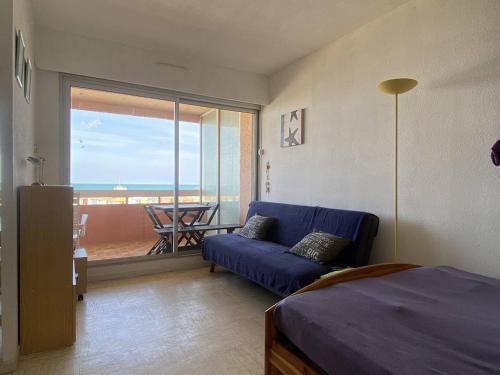 un salon avec un canapé bleu et un balcon dans l'établissement Studio vacances Le Barcarès, vue port, terrasse, parking - FR-1-782-81, au Barcarès