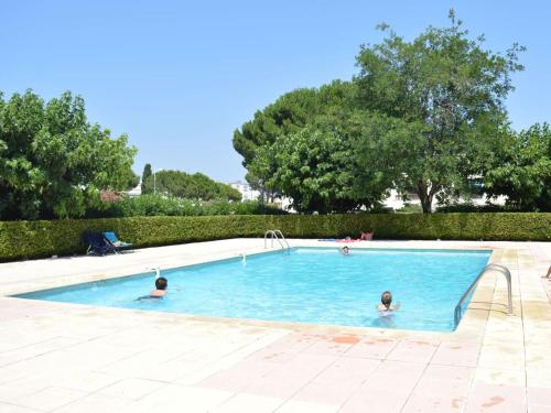 2 personnes nagent dans une piscine dans l'établissement Appt 2 pièces climatisé pour 4 pers, Le Grau-du-Roi - FR-1-250-314, au Grau-du-Roi