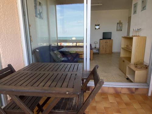 d'un salon avec une table en bois et une porte coulissante en verre. dans l'établissement Studio vacances Le Barcarès, vue port, terrasse, parking - FR-1-782-81, au Barcarès