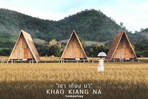 a woman with an umbrella walking through a field at Khao Kiang Na เขา เคียง นา in Ban Muang Kut