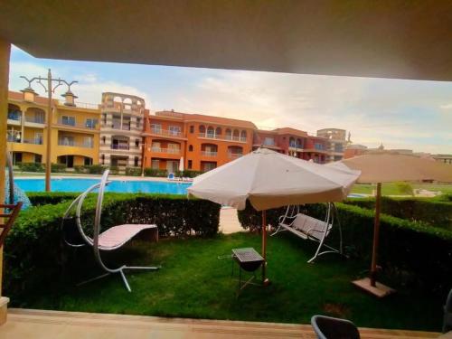 a yard with an umbrella and chairs and a pool at Porto Matrouh in Marsa Matruh