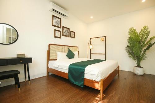 a bedroom with a bed and a desk and a plant at The Mira Villa West Lake by XÔI Residences in Hanoi