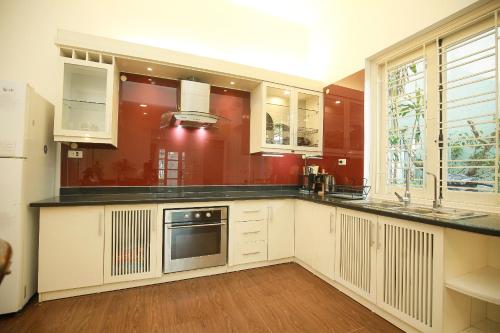 a kitchen with white cabinets and red walls at The Mira Villa West Lake by XÔI Residences in Hanoi