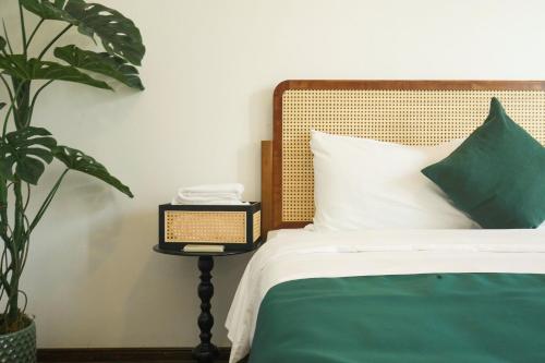 a bedroom with a bed and a night stand with a plant at The Mira Villa West Lake by XÔI Residences in Hanoi