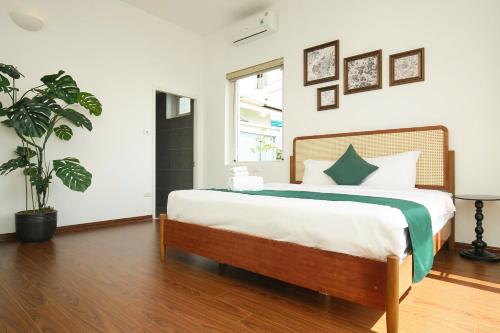 a bedroom with a large bed and a potted plant at The Mira Villa West Lake by XÔI Residences in Hanoi