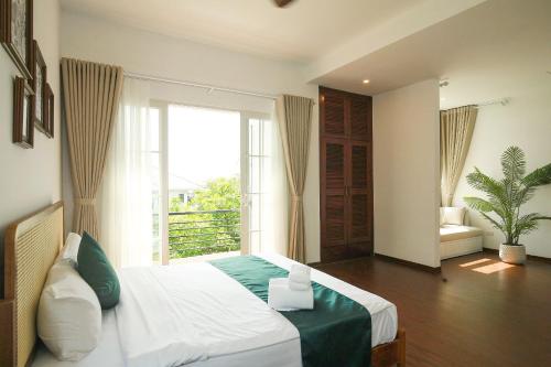 a bedroom with a bed and a large window at The Mira Villa West Lake by XÔI Residences in Hanoi