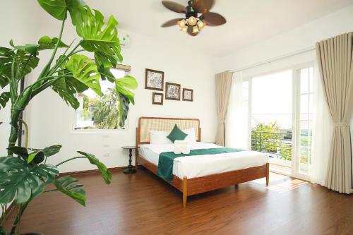 a bedroom with a bed and a ceiling fan at The Mira Villa West Lake by XÔI Residences in Hanoi