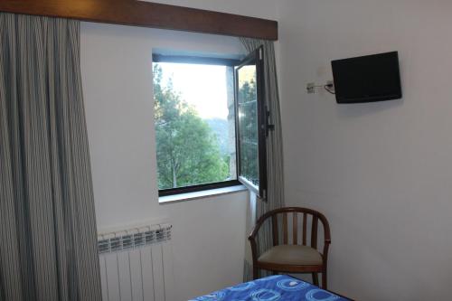a bedroom with a window and a bed and a chair at Pála dos Mouros in Geres