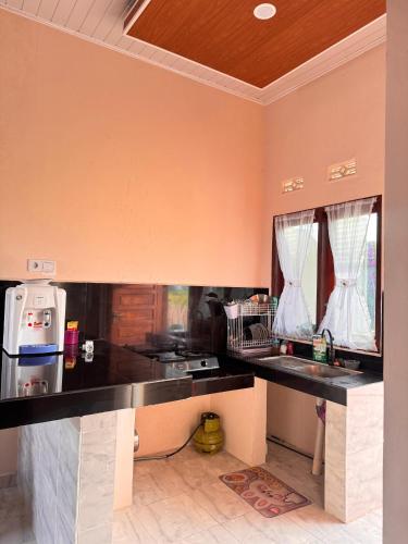 una cucina con piano di lavoro nero in una camera di Homestay Bukittinggi Agam "NADELS HOMESTAY SYARIAH" a Gadut