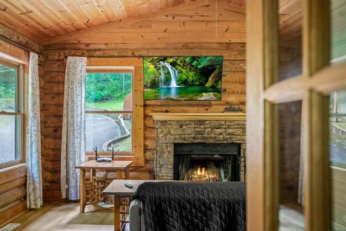 een open haard in een blokhut met een tv erboven bij Log Cabin, In-Room Jacuzzi, WiFi, Fireplace in Sevierville
