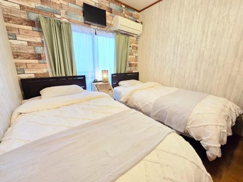 two beds in a room with a brick wall at 202 Airport and Disneyland direct bus Near Koiwa st in Tokyo