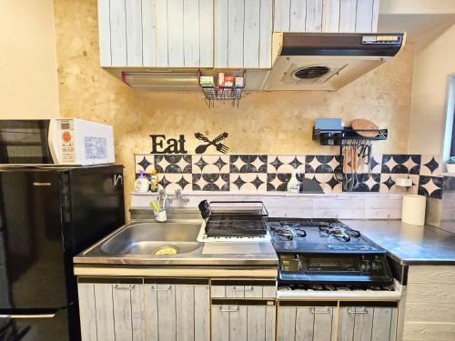 a kitchen with a sink and a black refrigerator at 202 Airport and Disneyland direct bus Near Koiwa st in Tokyo