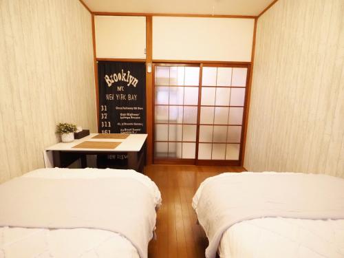 two beds in a room with a sign on the wall at 202 Airport and Disneyland direct bus Near Koiwa st in Tokyo